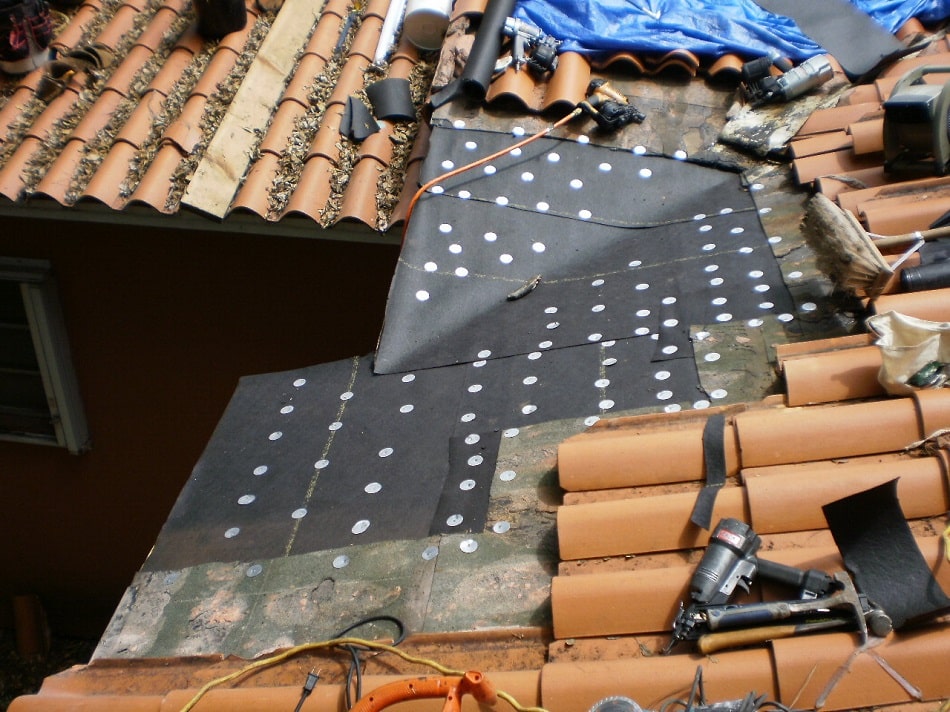 Clay tile roof opened up with new underlayment and cap nails installed before the tile goes back