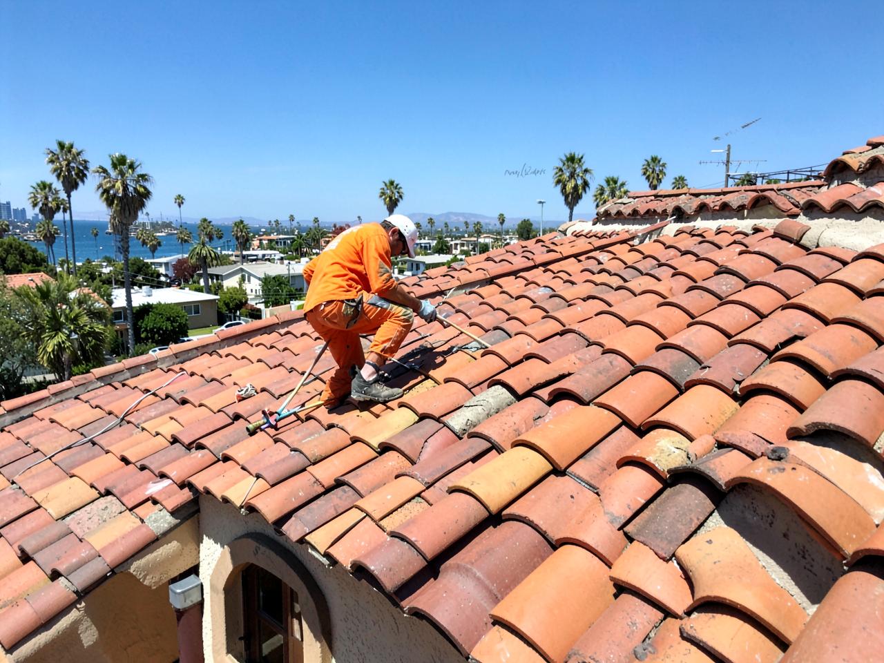 Roofer repairing clay barrel tile on a Southern California home
